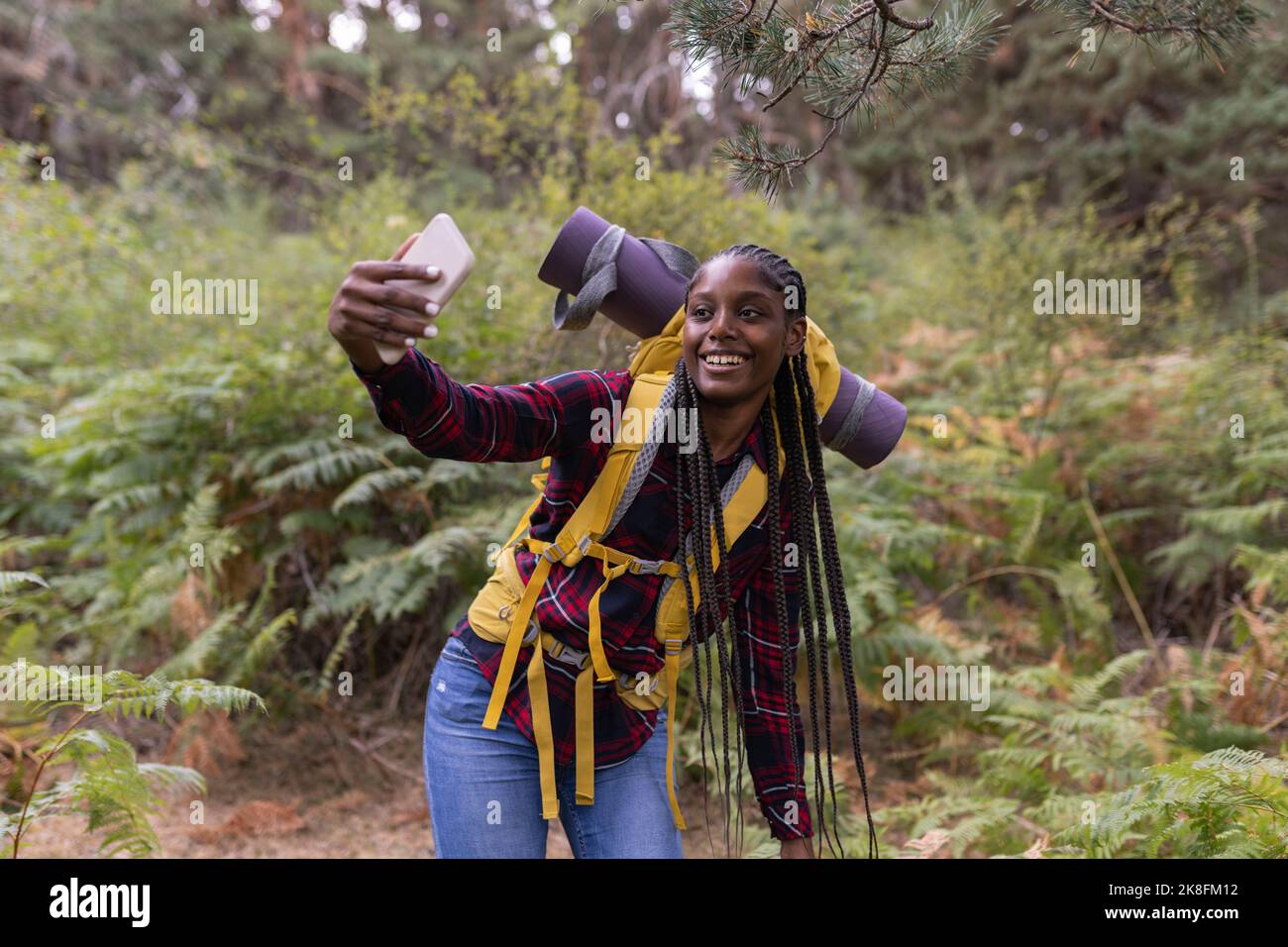 Felice giovane donna con zaino che prende selfie attraverso smartphone Foto Stock