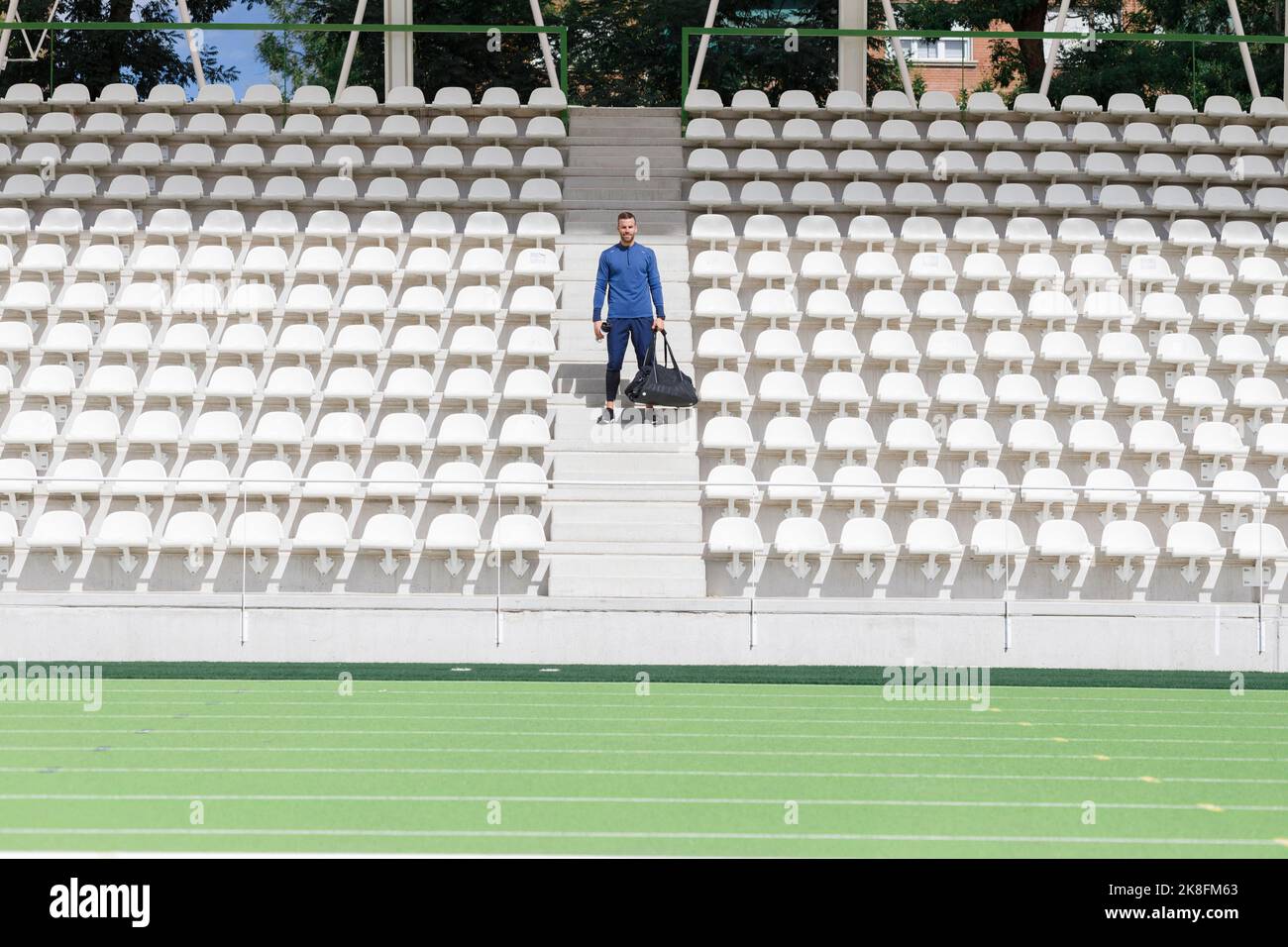 Atleta con borsa in piedi tra i sedili dello stadio Foto Stock