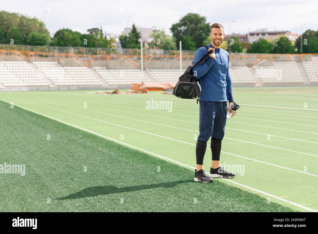 Sorridente sportivo in piedi sul campo sportivo Foto Stock