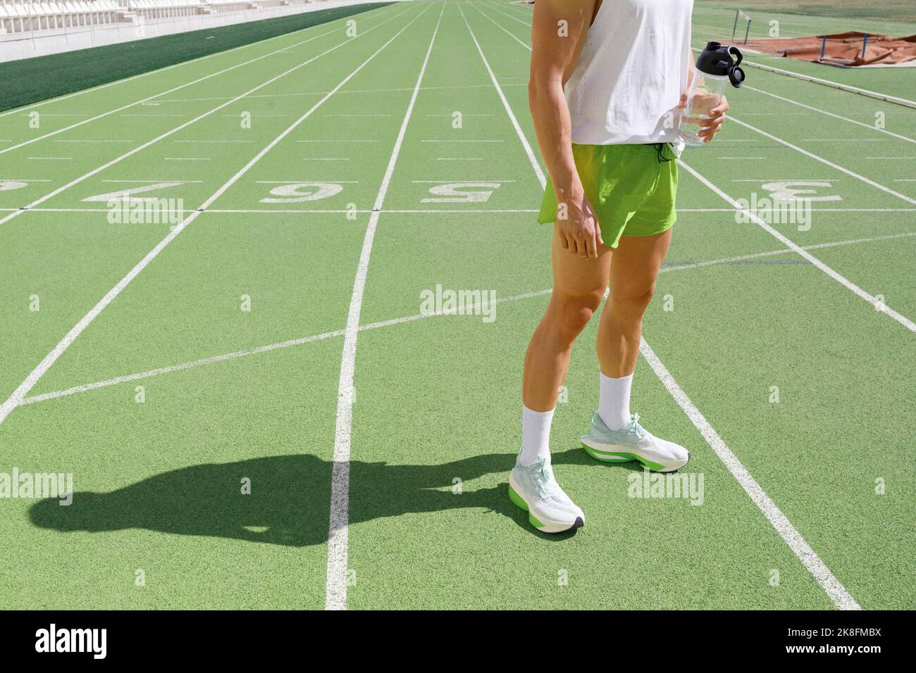 Atleta che tiene una bottiglia d'acqua in pista Foto Stock