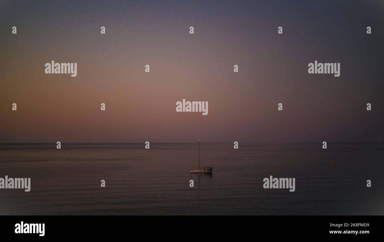 Barca a vela sul mare calmo al tramonto Foto Stock