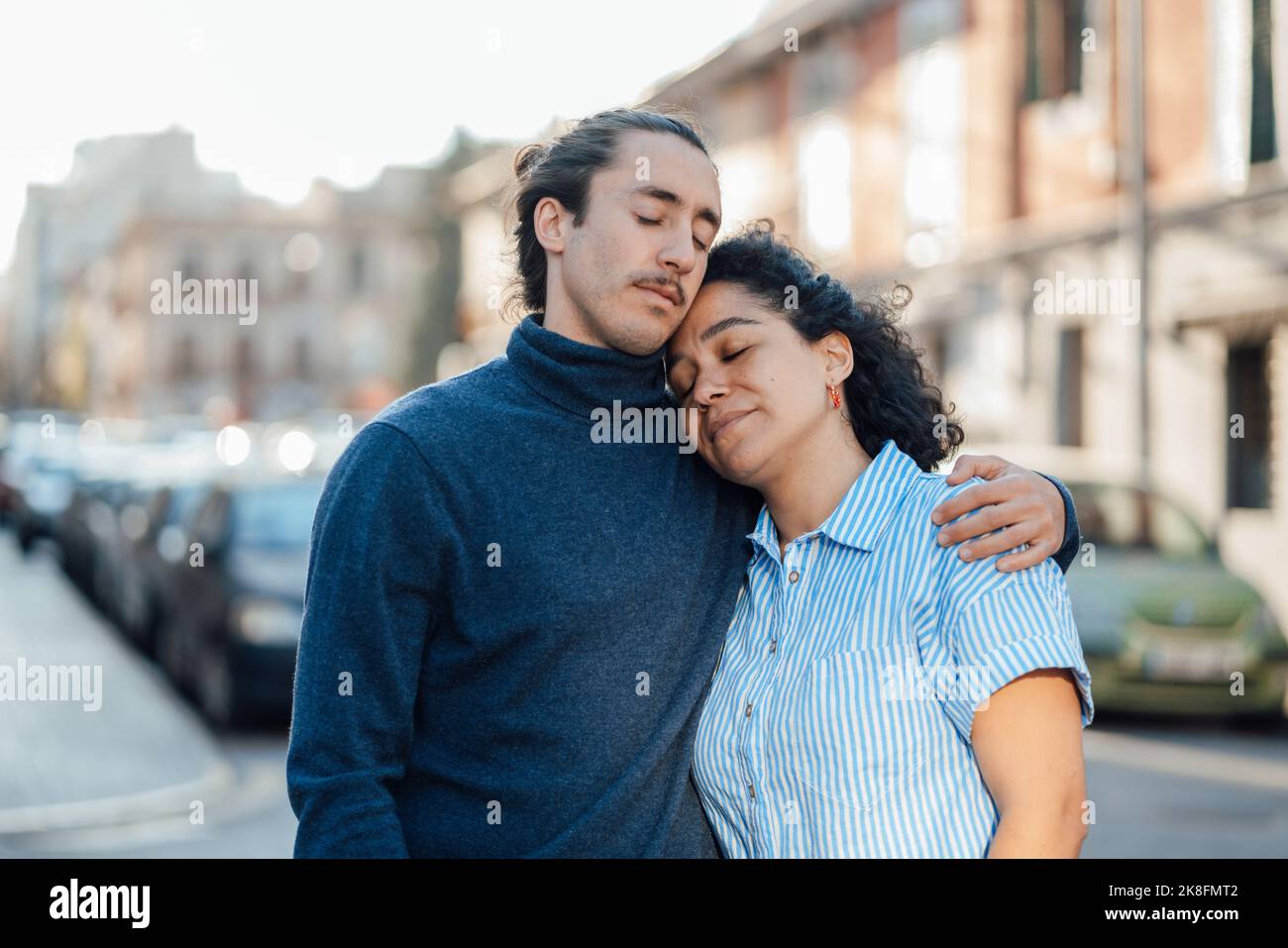 Giovane uomo braccio intorno di ragazza con gli occhi chiusi sulla strada Foto Stock