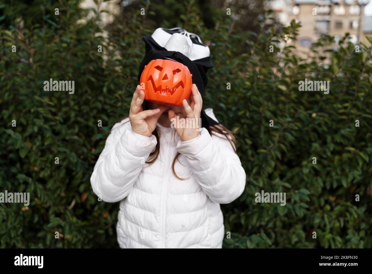 Ragazza che copre il viso con cesto di zucca in Halloween Foto Stock