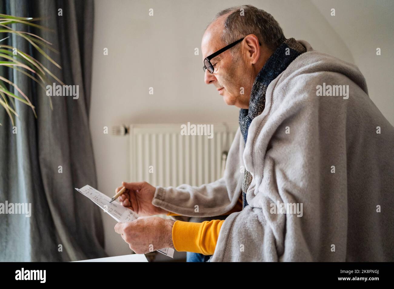 Uomo anziano che esamina la bolletta di riscaldamento nel paese Foto Stock