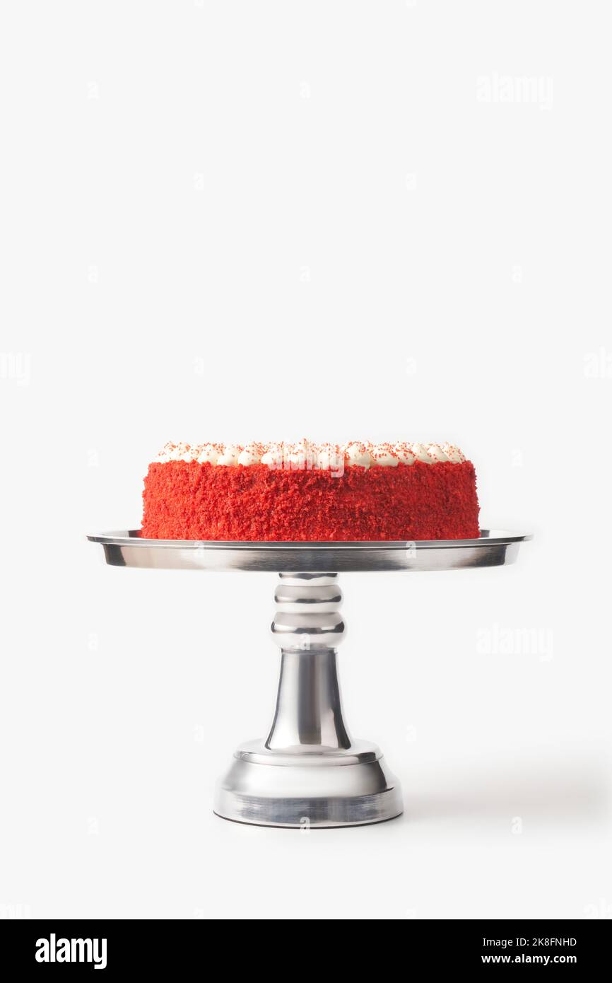 Deliziosa torta di velluto rosso fatta in casa su cakestand d'argento su sfondo bianco Foto Stock