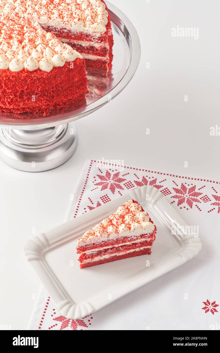 Fetta di torta di velluto rosso fresco su vassoio bianco sopra tovagliolo da tavolo Foto Stock