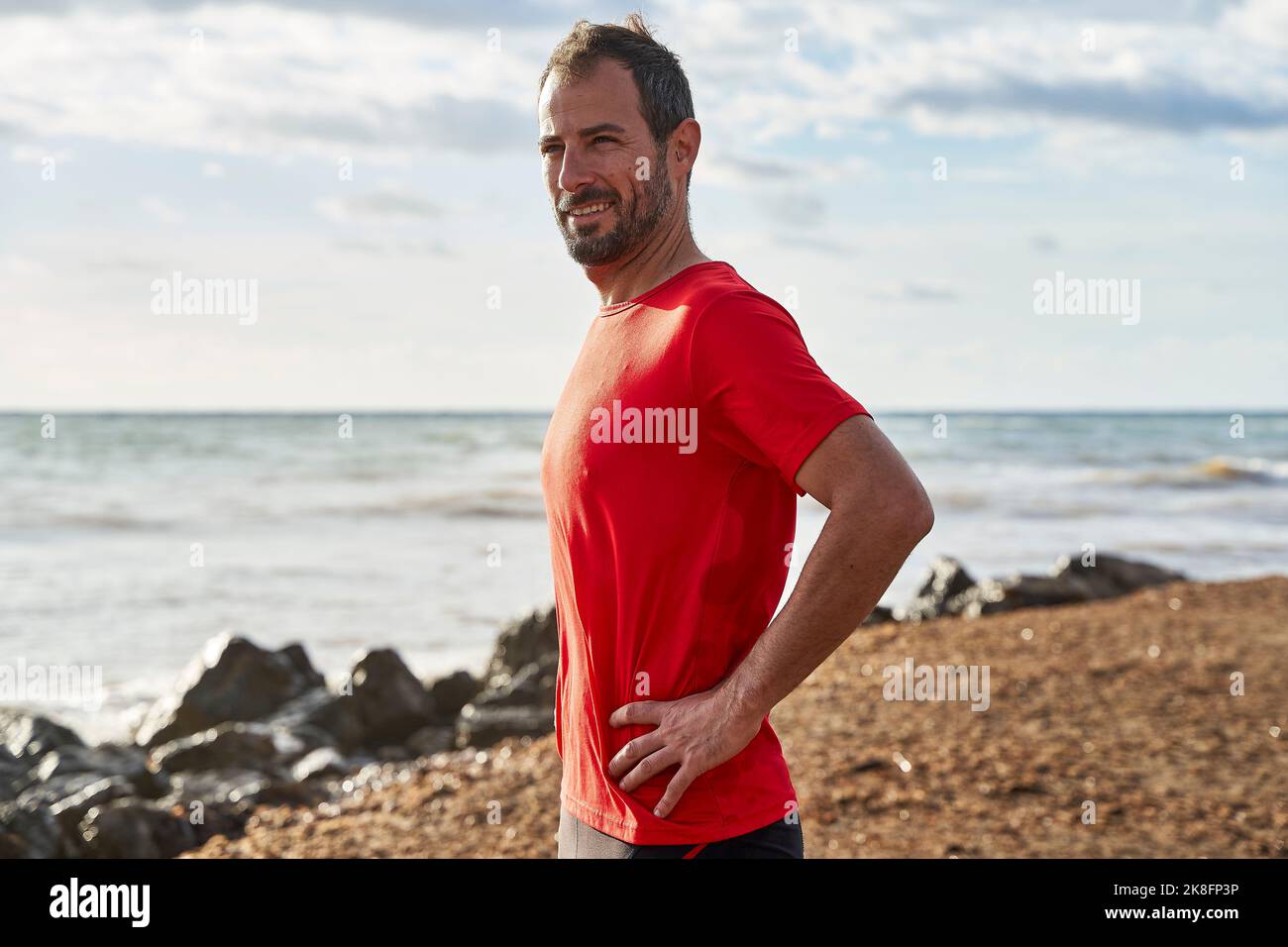 Uomo con mano sull'anca in spiaggia Foto Stock