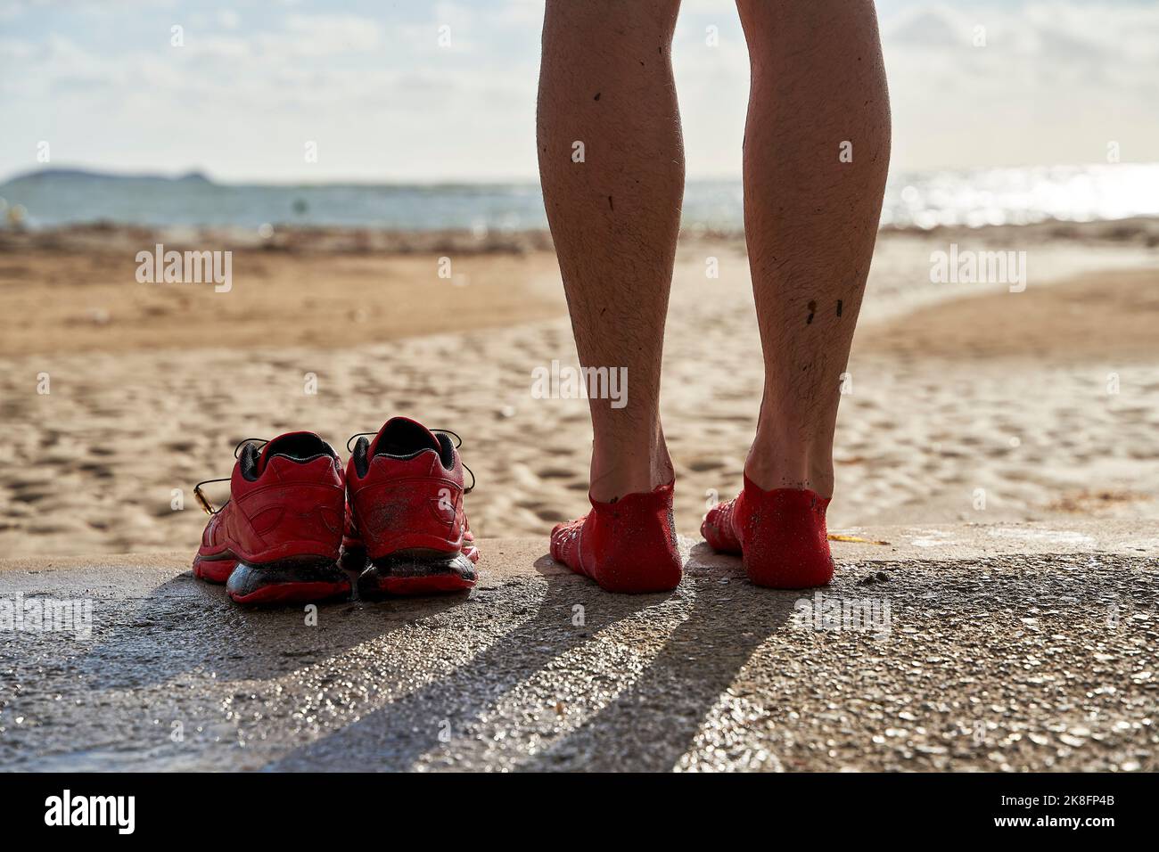 Gambe di uomo con scarpe sportive in spiaggia Foto Stock