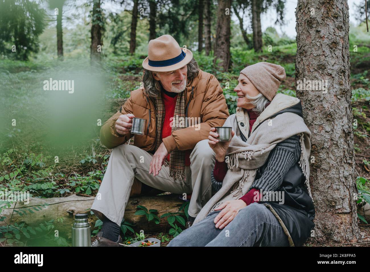 Felice coppia gustando tè caldo nella foresta Foto Stock