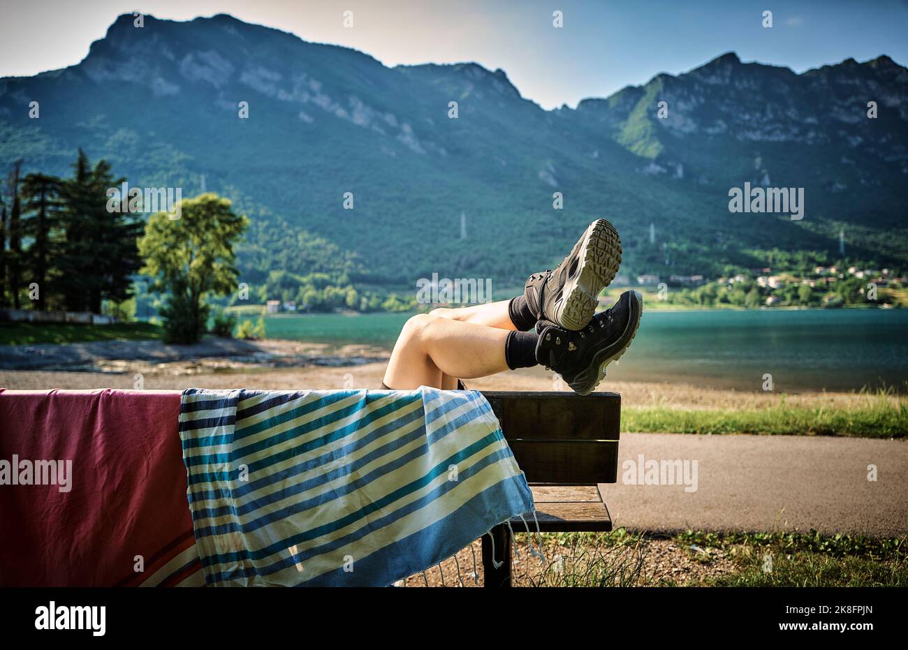 Gambe di donna che indossano stivali da trekking rilassarsi sulla panca con asciugamano Foto Stock