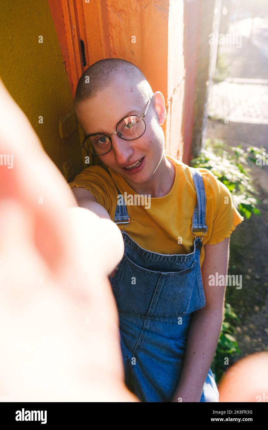 Persona non binaria con occhiali che prendono selfie Foto Stock
