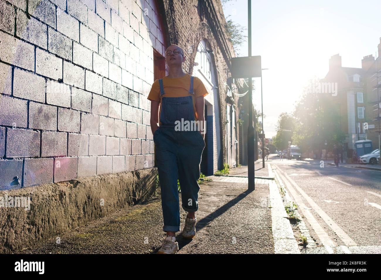 Giovane persona non binaria che cammina con le mani in tasche sul sentiero Foto Stock