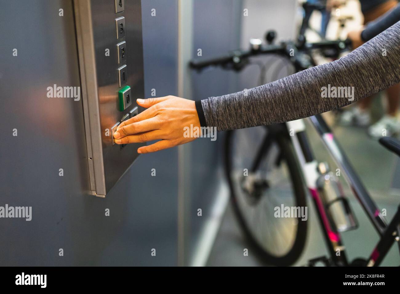 Donna mano che preme il pulsante di ascensore con bicicletta Foto Stock