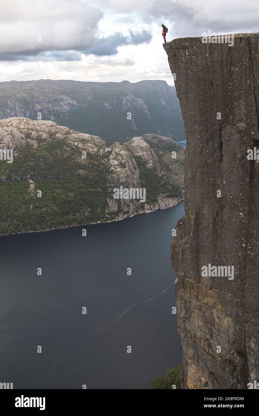 Escursionista in piedi sul bordo della maestosa scogliera di Pulpit presso il fiordo di Lysefjorden, Norvegia Foto Stock