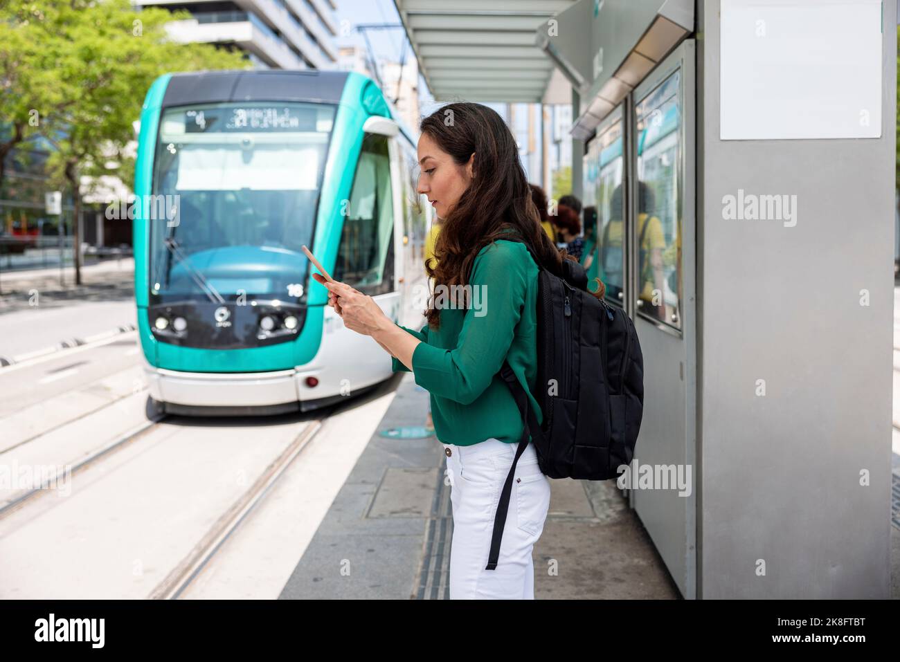 Donna che usa lo smartphone alla stazione del tram Foto Stock