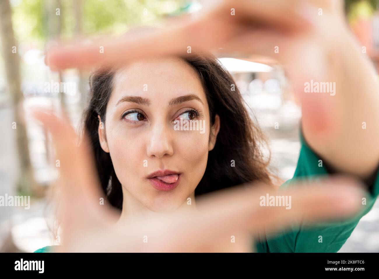 Donna che si stacca la lingua e che fa la cornice del dito con le mani Foto Stock