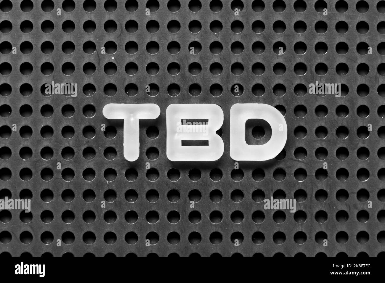 Lettera dell'alfabeto bianco in parola TBD (abbreviazione di da definire, discutere, determinare, decidere, cancellare o dichiarare) su sfondo nero di pegboard Foto Stock