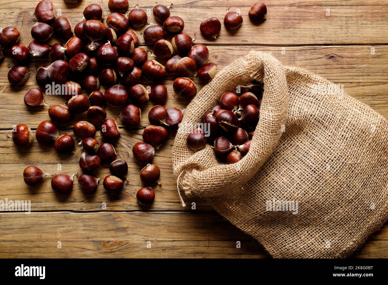 Vista dall'alto delle castagne fresche in sacco su un vecchio tavolo di legno Foto Stock