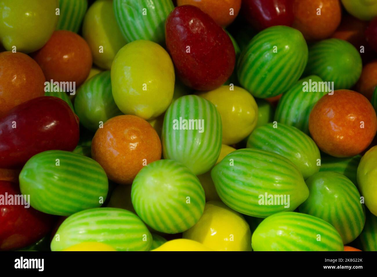 Tante caramelle masticate sotto forma di frutta: mela, arancia, limone, anguria in una glassa lucida. Dolce sfondo luminoso. Foto Stock