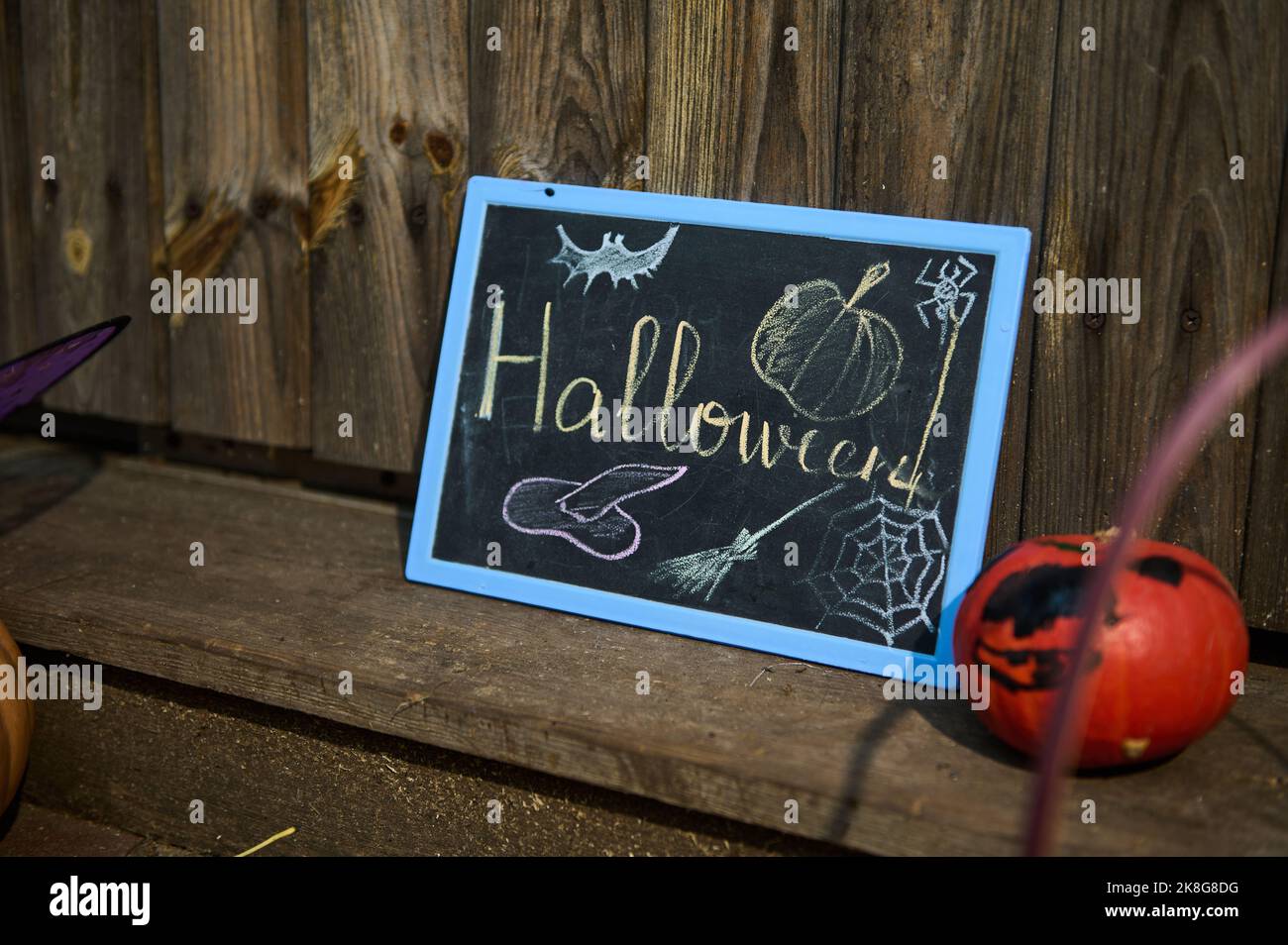 Una lavagna scritta Halloween su una soglia di legno e una piccola zucca arancione brillante. Ottobre 31. Decorazione domestica Foto Stock