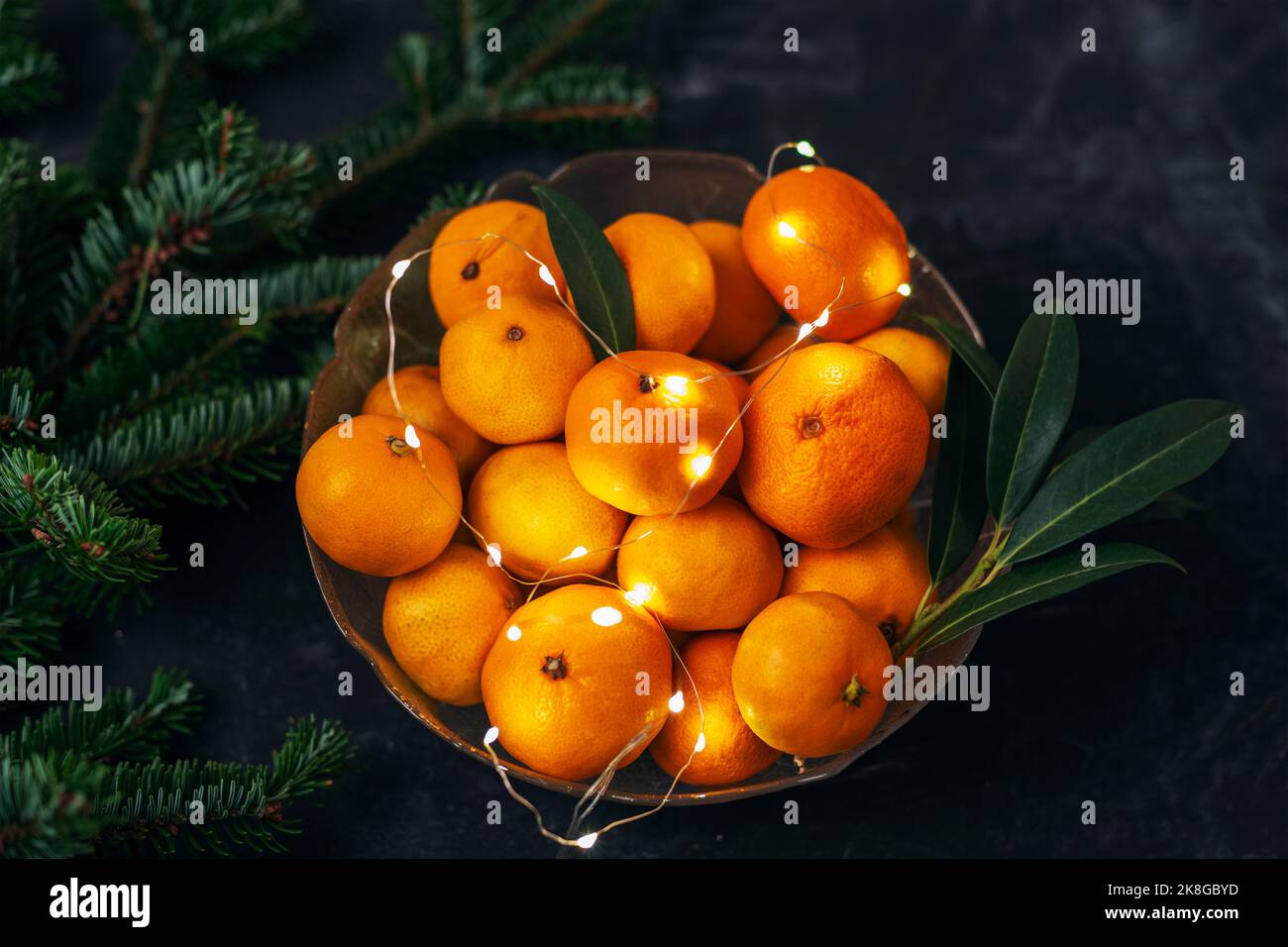 Ciotola con tangerini freschi, luci di Natale e rami di abete. Vista dall'alto Foto Stock