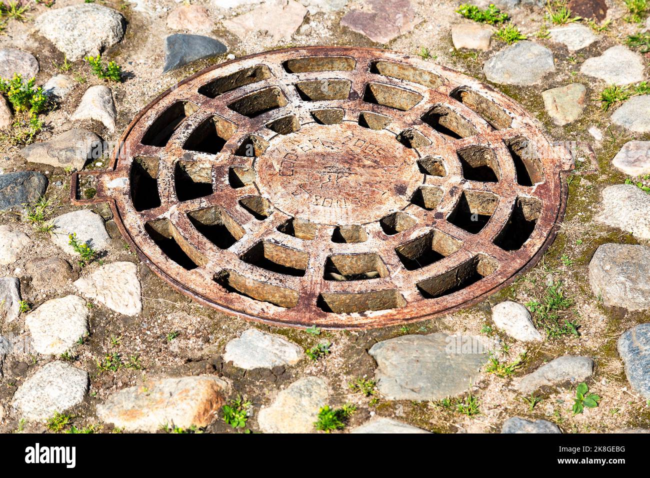 Samara, Russia - 21 ottobre 2022: Copertura del tombino in metallo arrugginito sulla strada urbana. Pozzetto di raccolta circolare per fognature Foto Stock