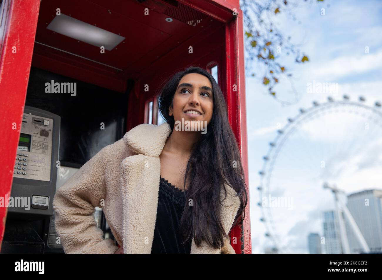 Ritratto di una ragazza a Londra sorridente in una cassetta telefonica. Foto Stock