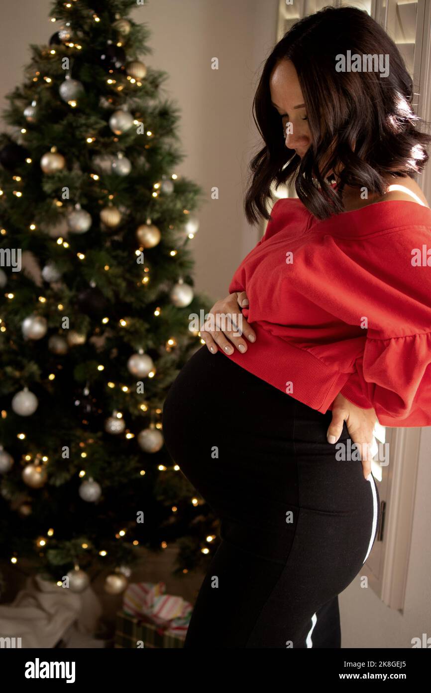 Bella donna incinta appesa palla di Natale su albero Foto Stock