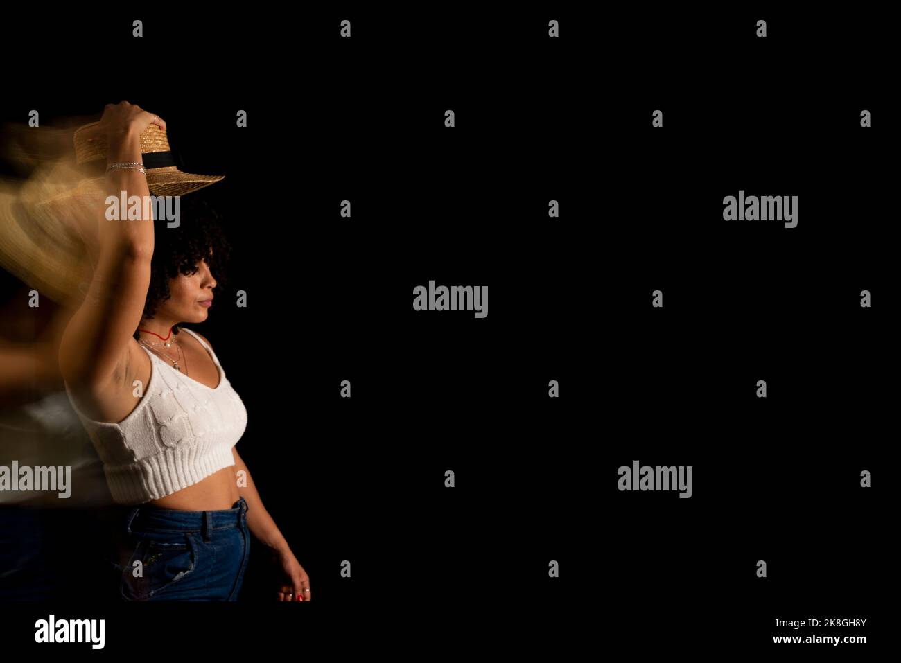 Vista temporizzata della donna che muove un cappello. Esposizione lunga, sfocatura del movimento. Donna felice. Salvador, Brasile. Foto Stock