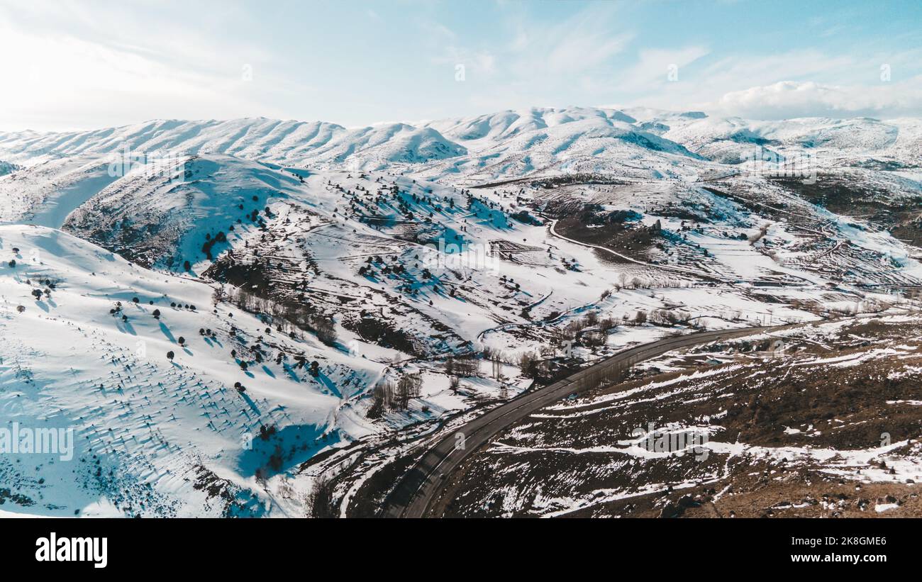 Vista mozzafiato del drone di strada asfaltata che va nella valle vicino alle piste di montagne innevate nella fredda giornata invernale in Turchia Foto Stock