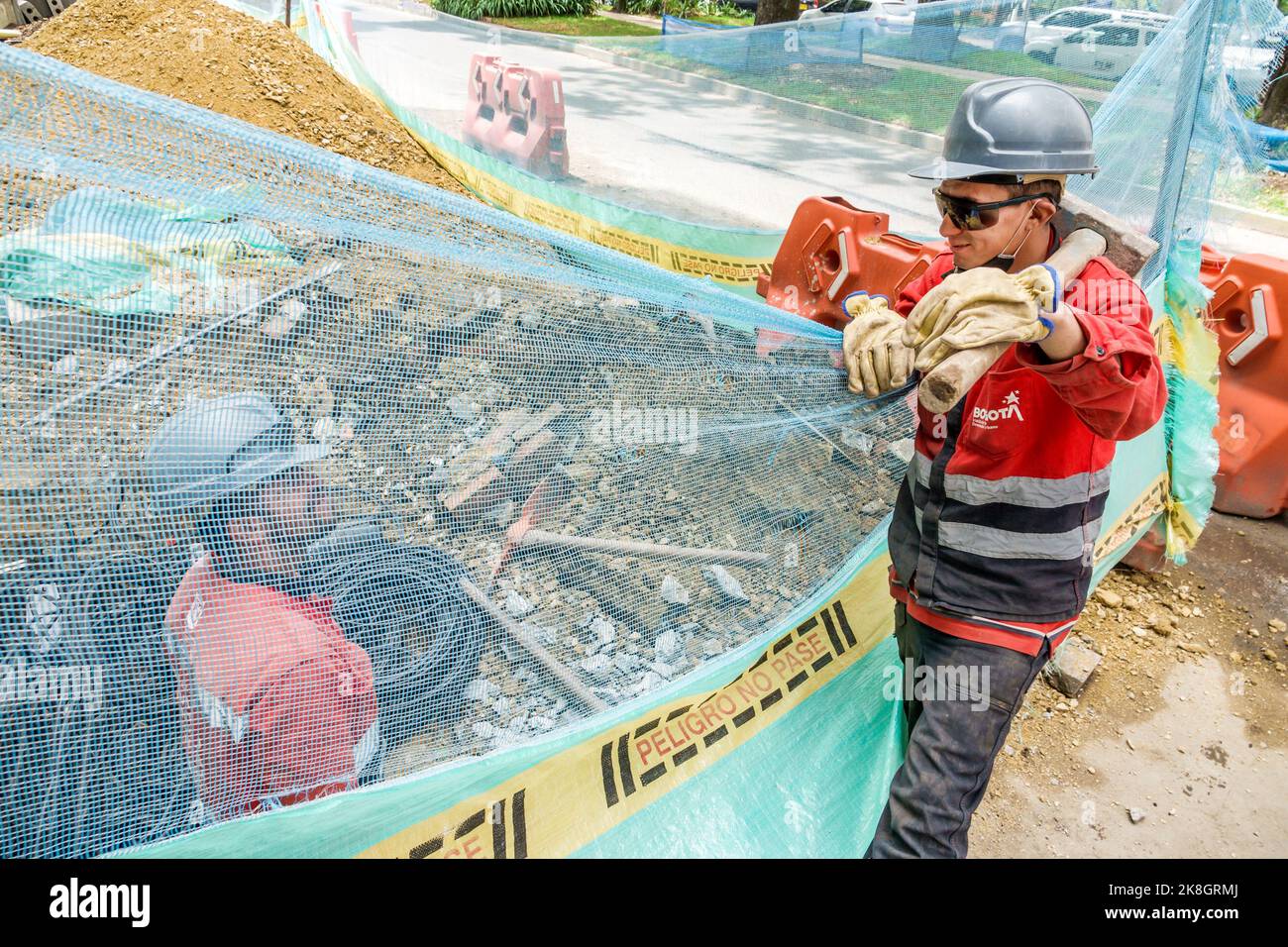 Bogota Colombia, El Chico Calle 94, sotto il nuovo sito di costruzione indossare elmetto cappelli capitale miglioramenti mesh barriera città elettrica acqua utilità, uomo Foto Stock