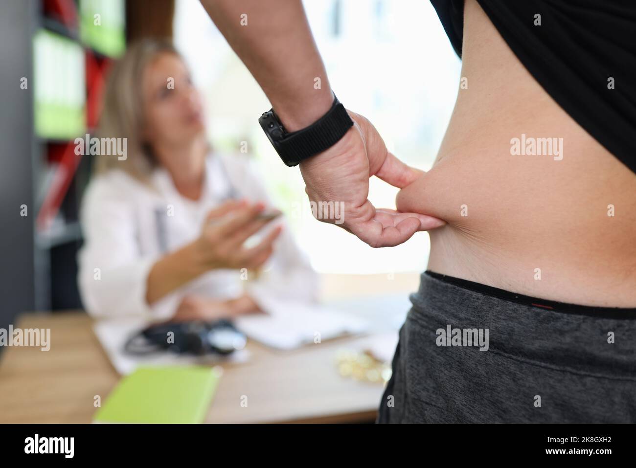 Uomo che tira la pelle sull'addome, mostrando il grasso corporeo nella zona addominale Foto Stock