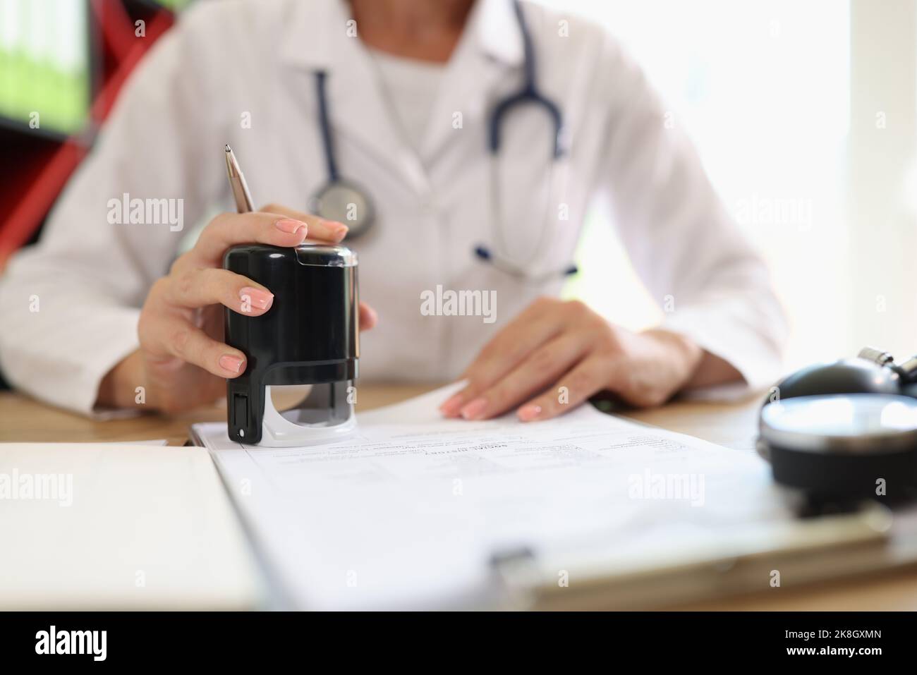 Dottore di sesso femminile che appone il timbro sui documenti medici o sulla prescrizione medica Foto Stock