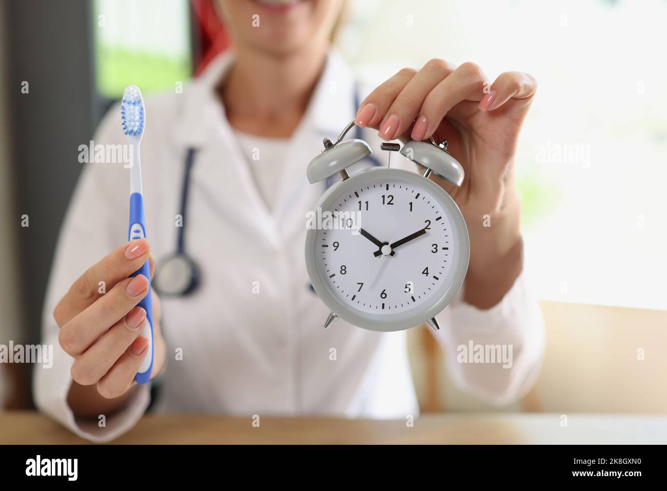 Una medico stomatologa che tiene in mano lo spazzolino e la sveglia Foto Stock