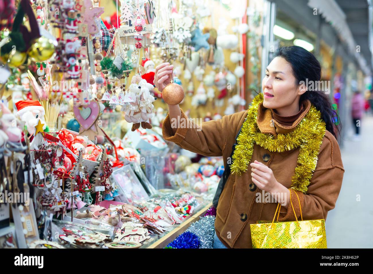 Ritratto di donna asiatica che sceglie i giocattoli di Natale al mercato di Natale Foto Stock