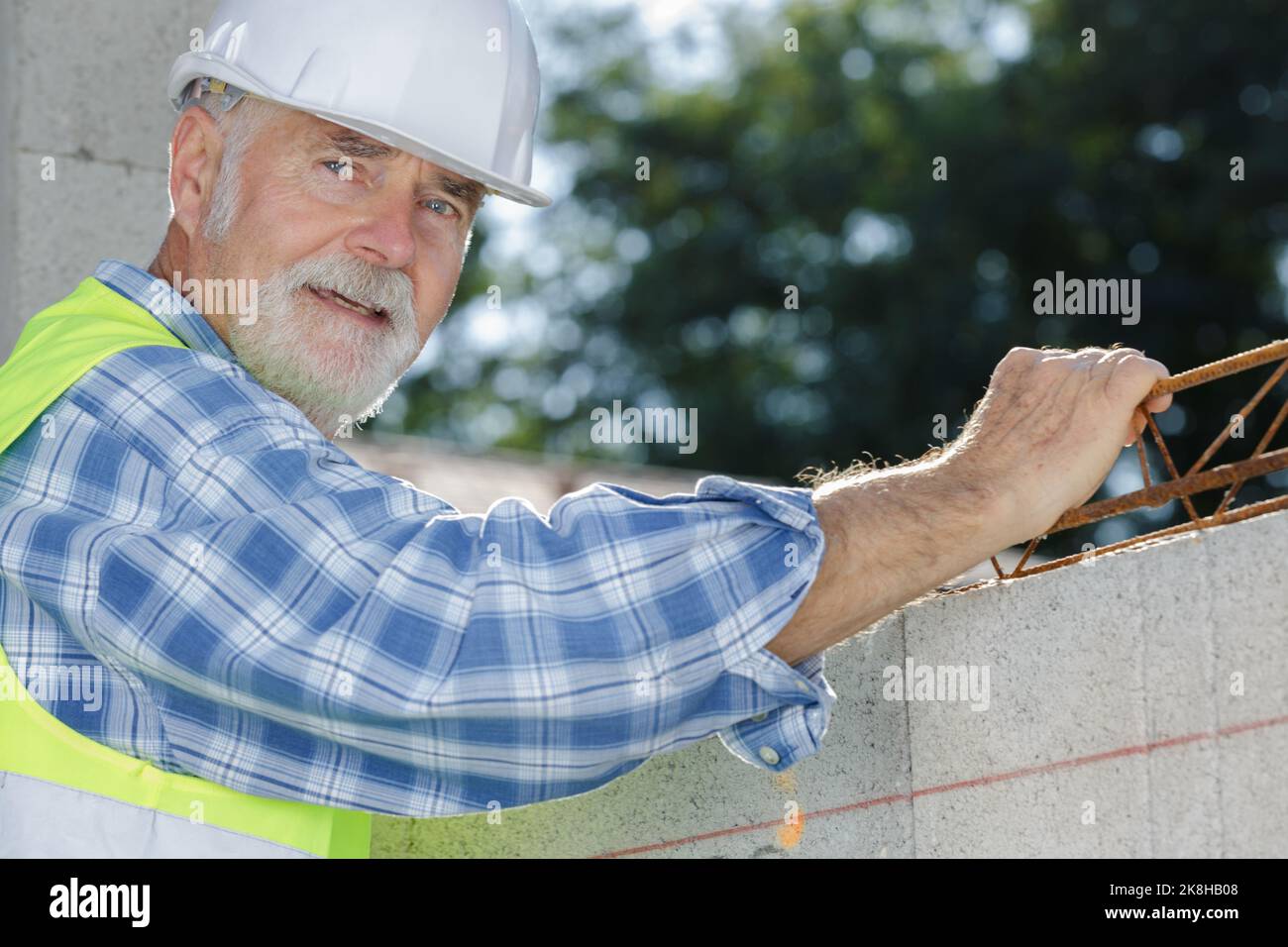 armatura di montaggio muratore senior tra lo strato di blocchi di calcestruzzo Foto Stock