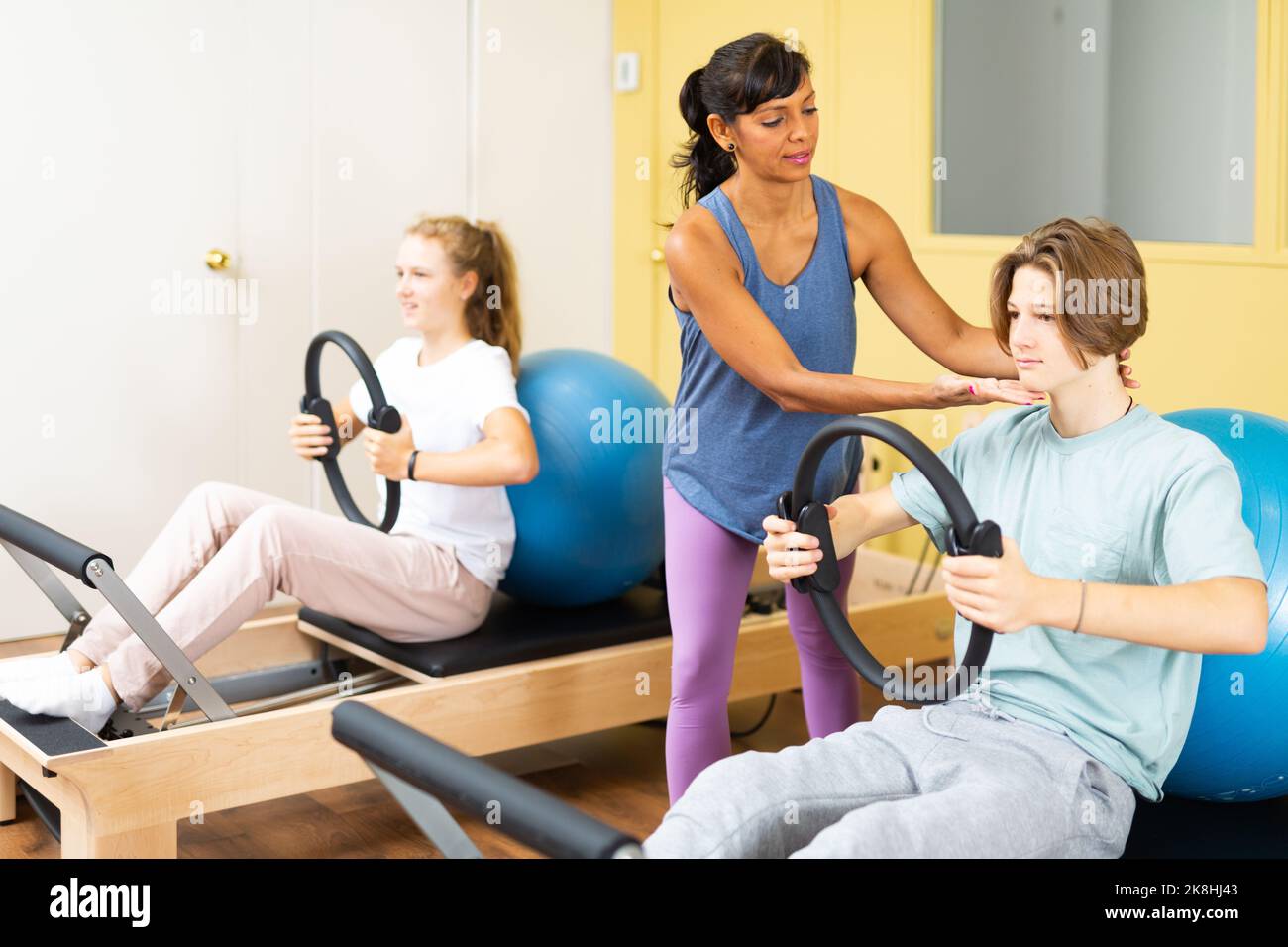 Gli adolescenti eseguono le esercitazioni con un anello di ginnastica sotto la guida del formatore Foto Stock Gli adolescenti eseguono le esercitazioni con un anello di ginnastica sotto la guida del formatore Foto Stock