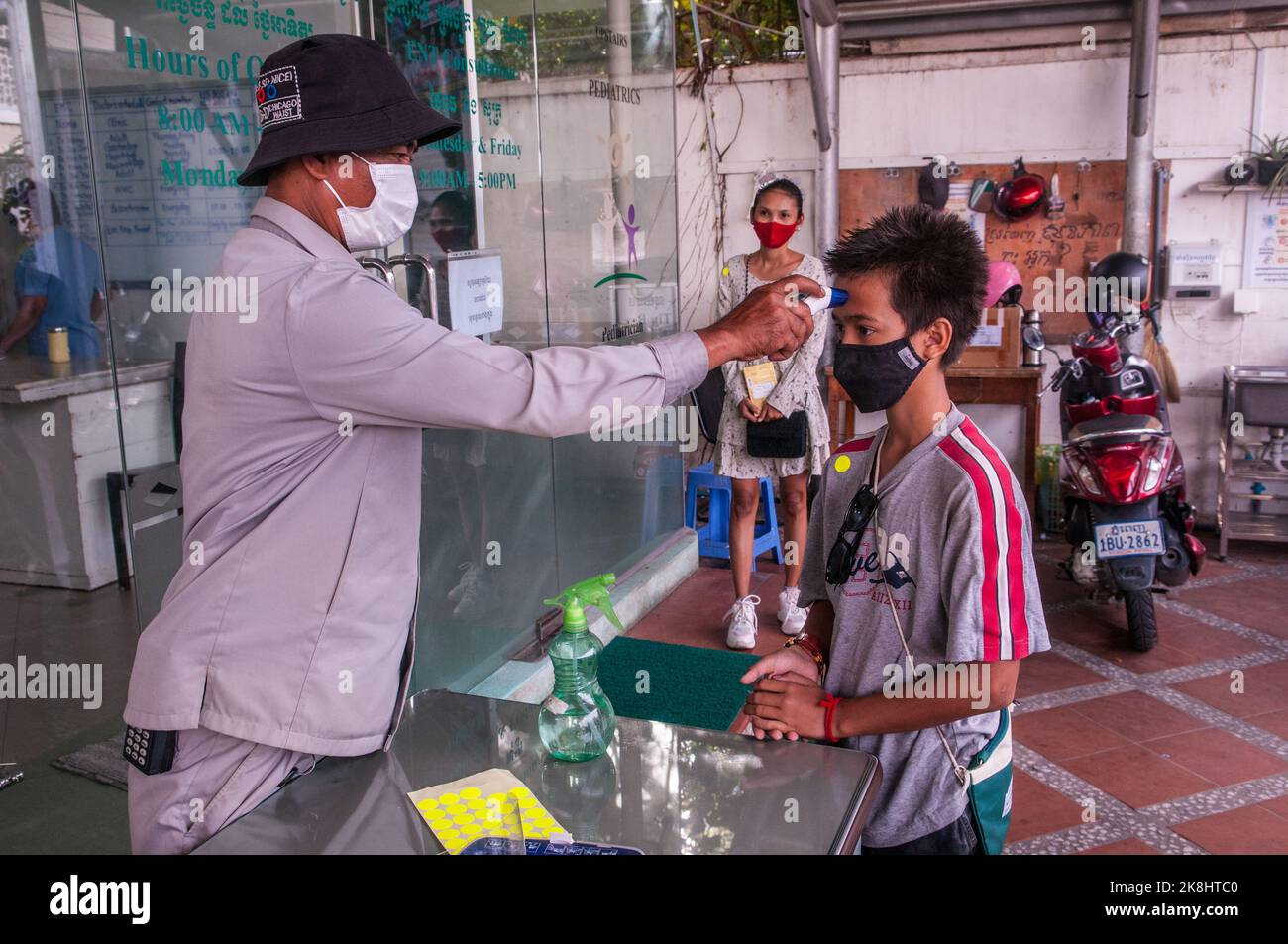 Durante uno scoppio di COVID - 19, un ragazzo di razza mista (cambogiano - americano) ottiene la sua temperatura controllata, Phnom Penh, Cambogia. © Kraig Lieb Foto Stock