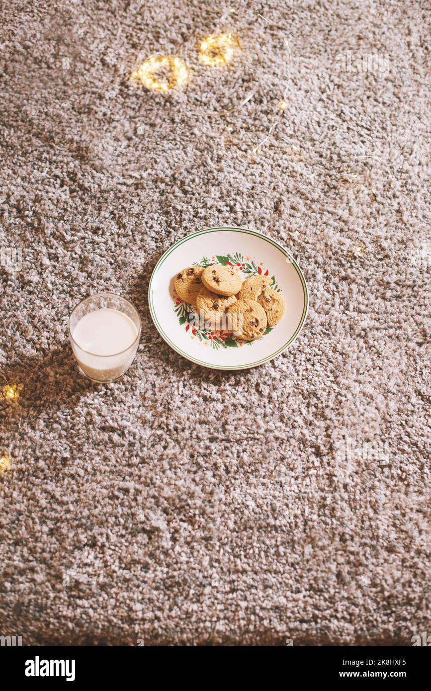 Bicchiere di latte e piatto con biscotti in attesa di Babbo Natale a casa la vigilia di Natale credenza nella fiaba Foto Stock