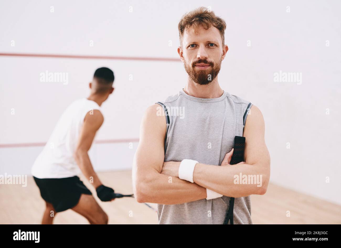 La determinazione vince ogni volta. Ritratto di un giovane che gioca una partita di squash con i suoi compagni di squadra sullo sfondo. Foto Stock