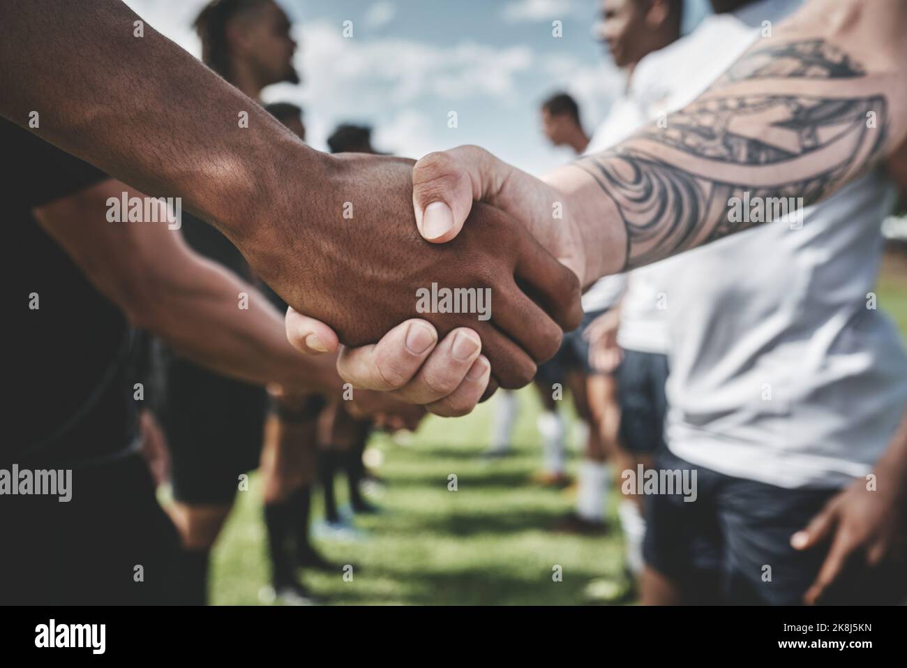 Il segno dello sport. Un gruppo di giovani giocatori di rugby che si scuotono le mani per congratularsi nel giocare un buon gioco all'aperto su un campo. Foto Stock