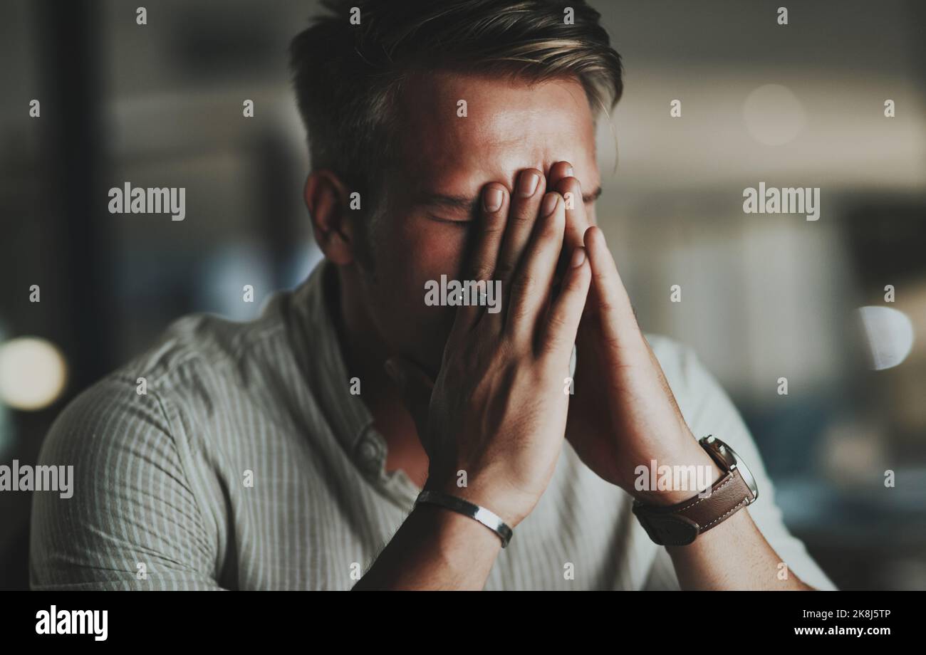 Mi arrendo, un giovane uomo d'affari che guarda stressato mentre lavora in un ufficio di notte. Foto Stock