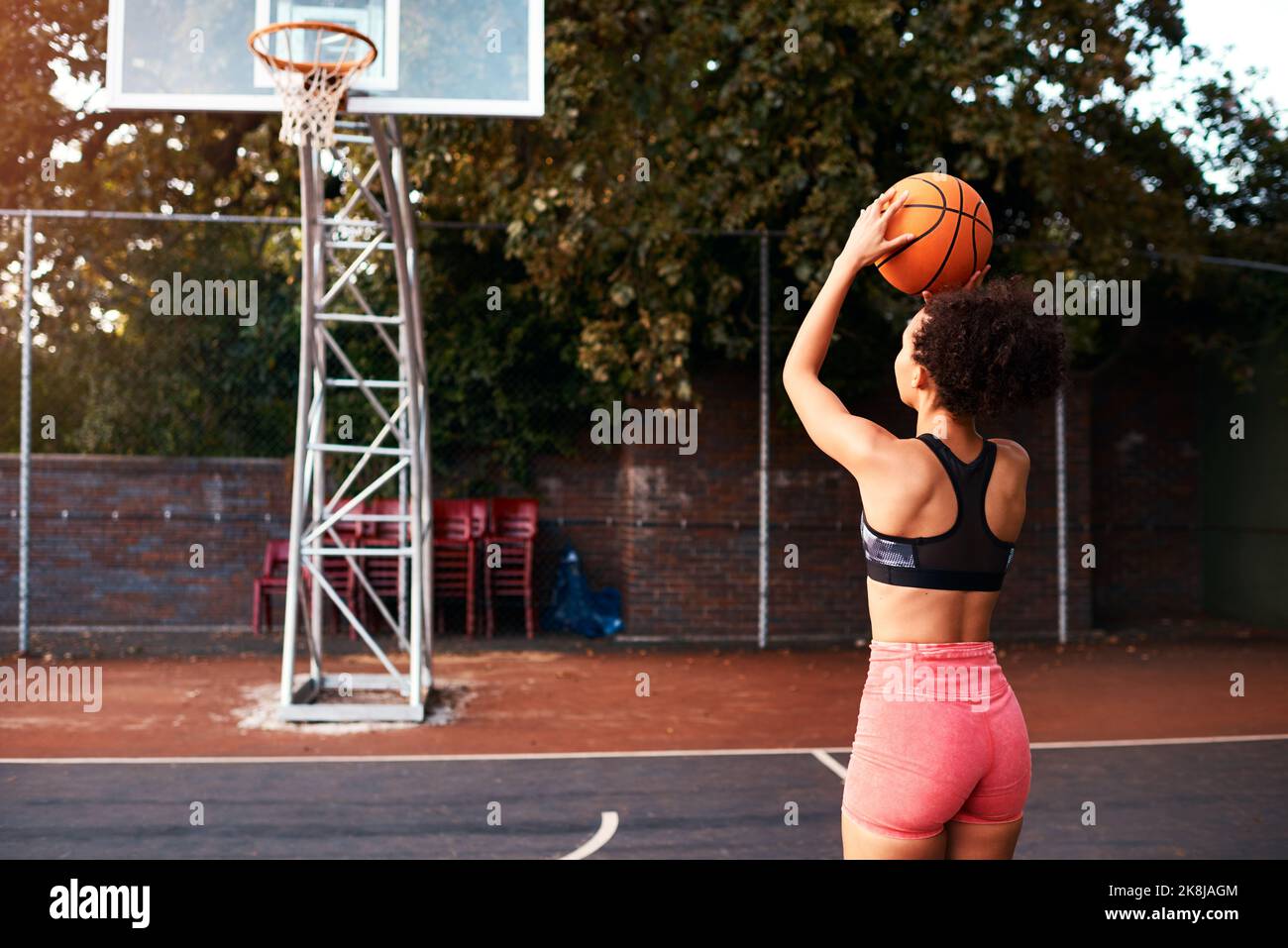 Ottenere in alcuni colpi di pratica. Scatto a tutta lunghezza di un giovane sportivo attraente che si alza da solo su un campo da basket e si scalda con la palla. Foto Stock