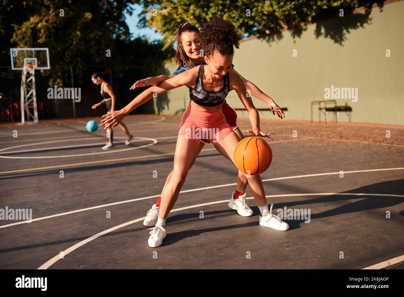 Un giovane sportivo che blocca il suo avversario durante una partita di basket durante il giorno. Foto Stock