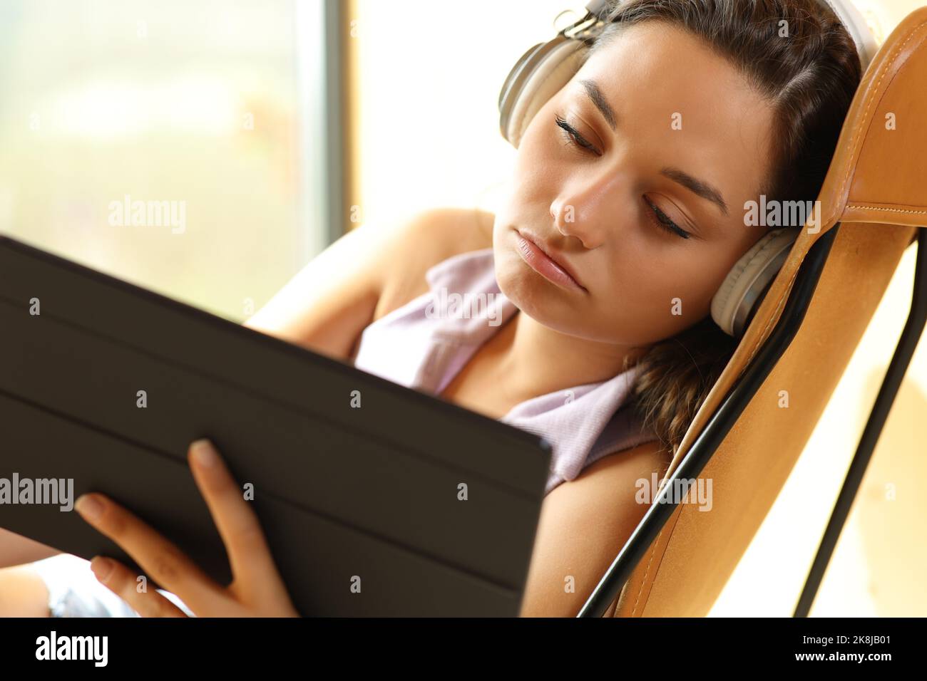 Annoiato donna che guarda i video sul tablet seduto a casa Foto Stock