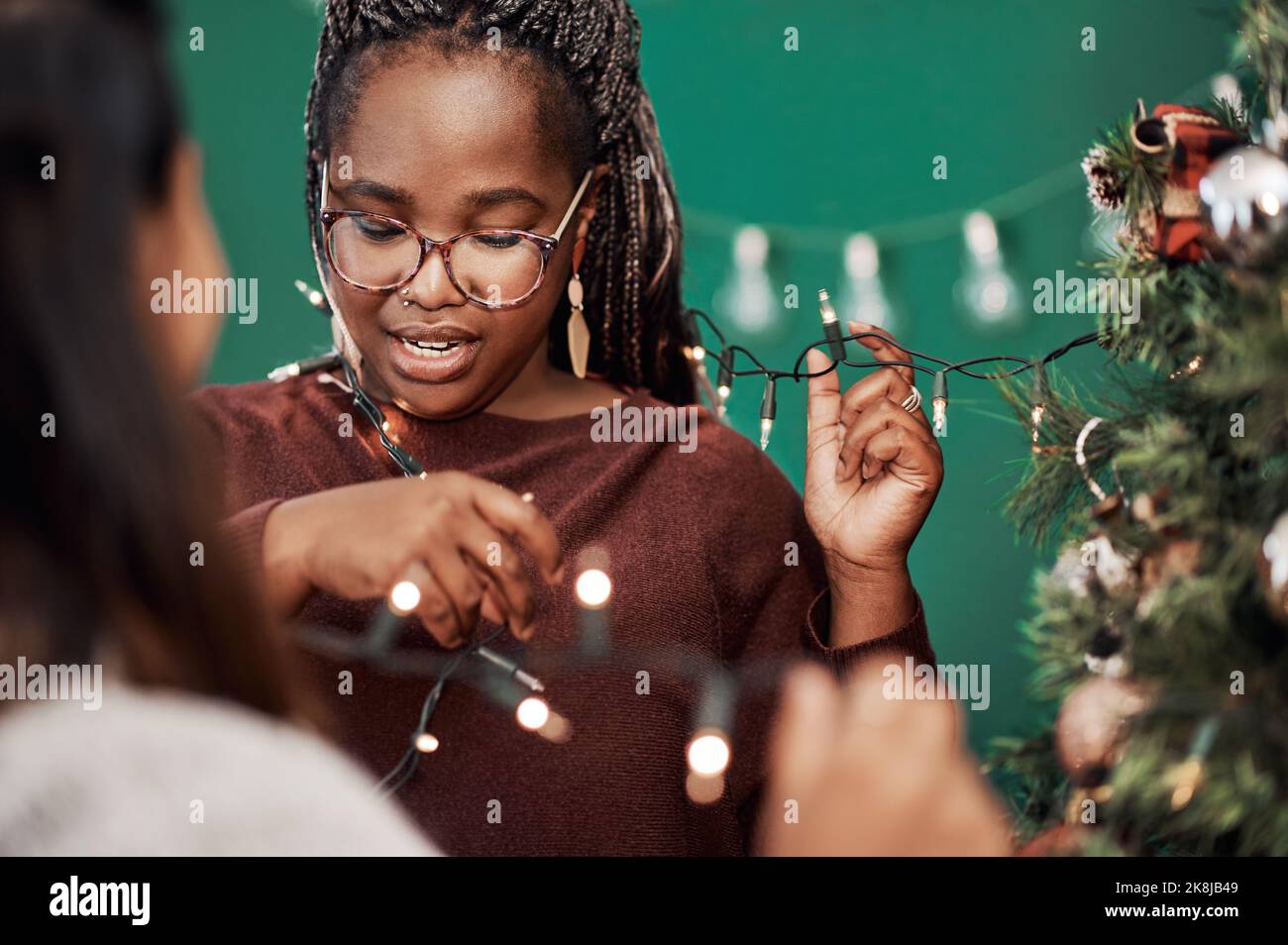 Un momento per stare con le persone che amate di più. Due giovani donne che decorano un albero di Natale a casa. Foto Stock