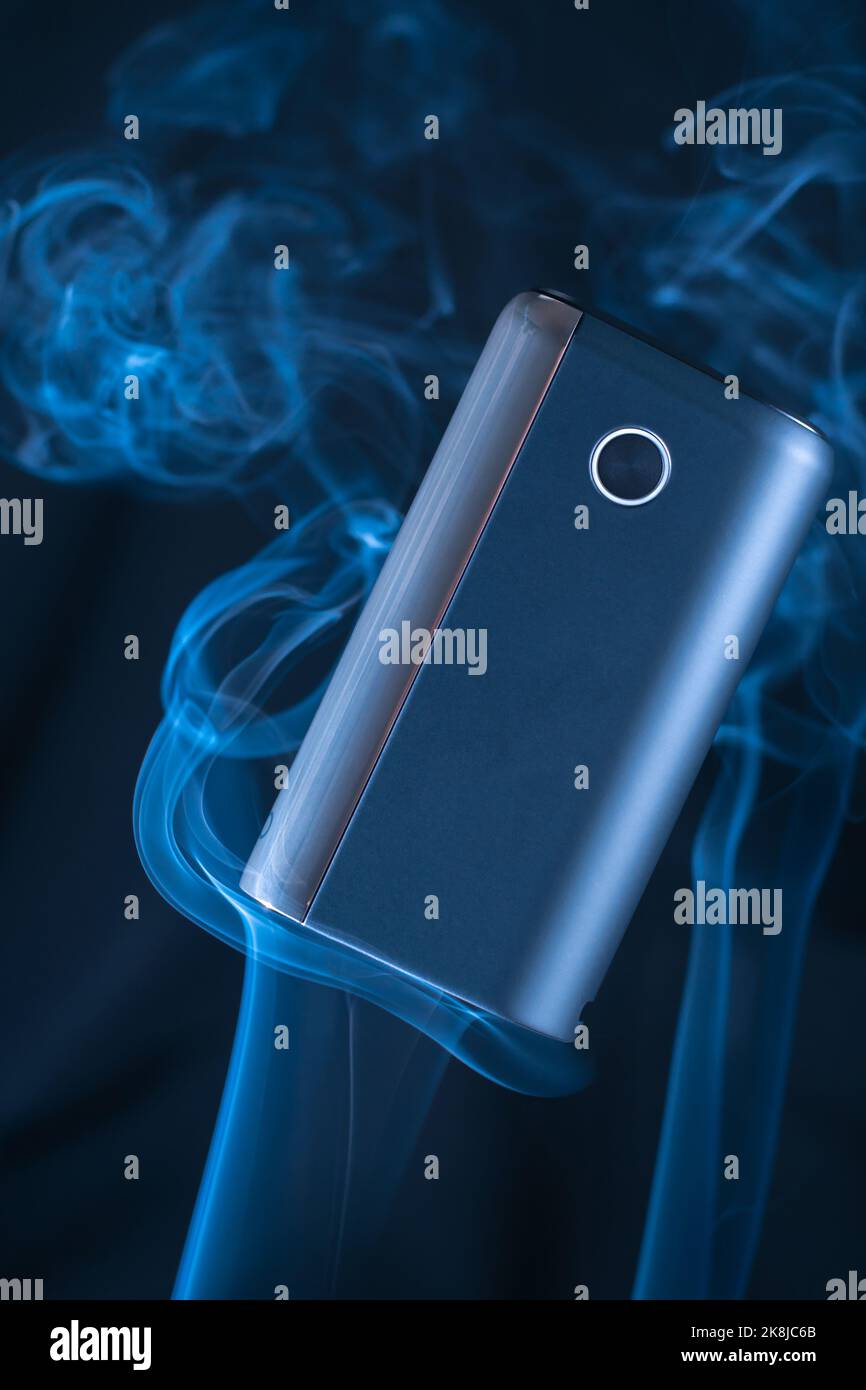 Il nuovo dispositivo di riscaldamento per fumo nero GLO galleggia in soffi di fumo bianco al neon blu. Sigarette elettroniche moderne Foto Stock