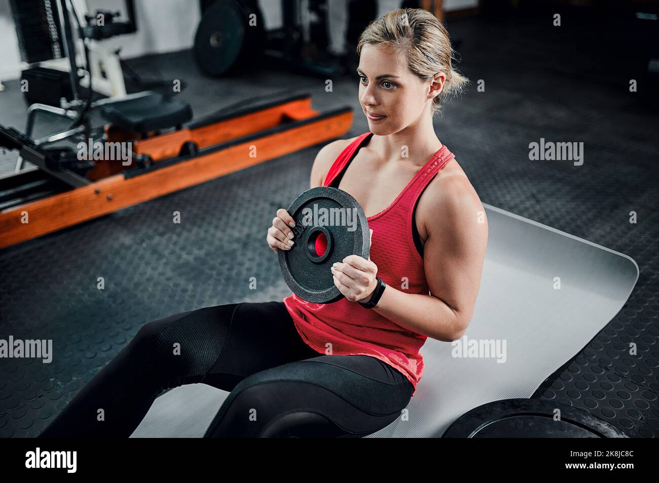 Shes hardcore. Inquadratura ad angolo alto di una giovane atleta attraente che fa situps con un peso in palestra. Foto Stock