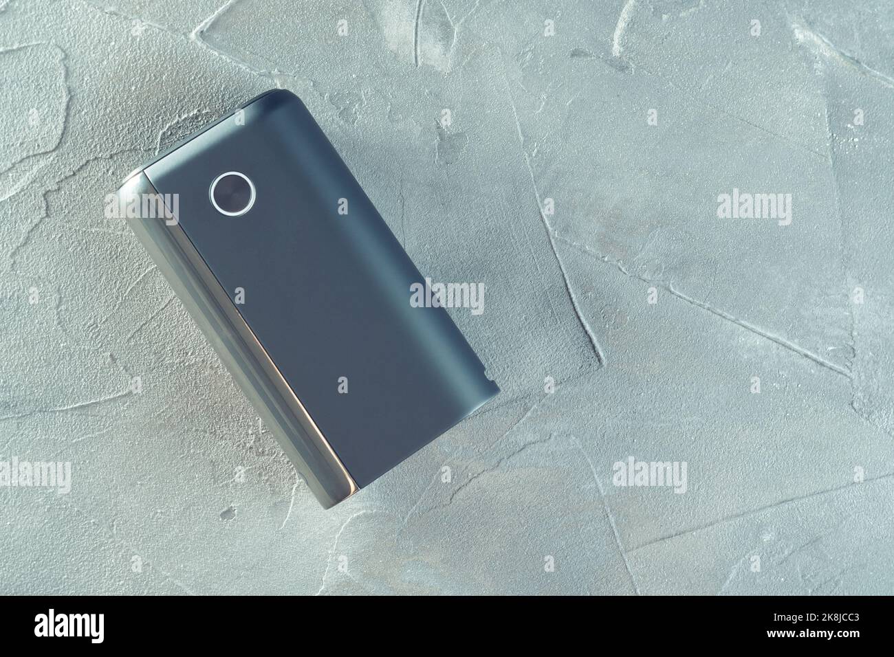 Nuovo dispositivo di riscaldamento per fumo nero GLO su superficie grigia in cemento. Sigarette elettroniche moderne. Spazio di copia piatto Foto Stock