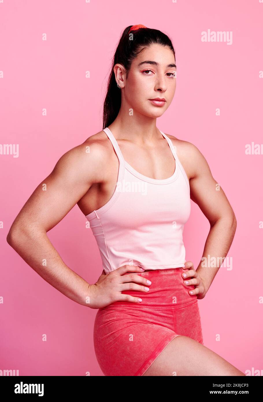 Rimanere dedicati e disciplinati. Studio ritratto di una giovane donna sportiva che posa con le mani sui fianchi su uno sfondo rosa. Foto Stock